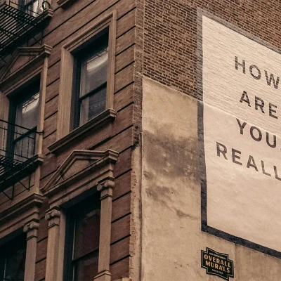 A photo of a building with a sign that reads "How are you, really?"