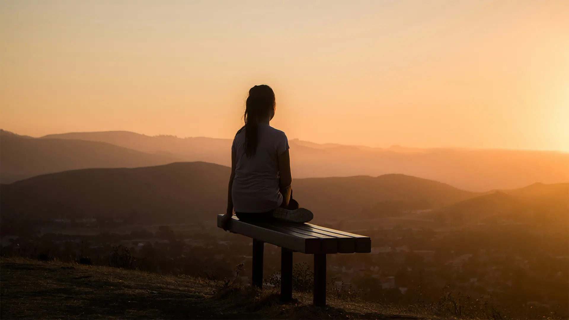 Woman sitting on a bench, looking at a vista