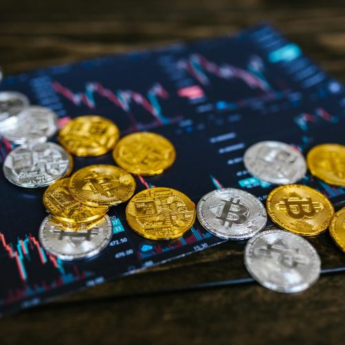 Gold and silver Bitcoin coins on financial graph, symbolizing cryptocurrency trading and digital currency wealth.